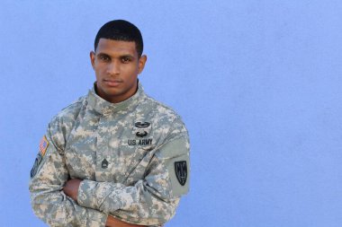 Mavi duvarın önünde üniformalı yakışıklı Afro-Amerikan askerinin yakın plan portresi