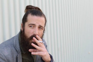 Sigara içen yakışıklı sakallı adamın portresi. Erkek saçı olan hippi..