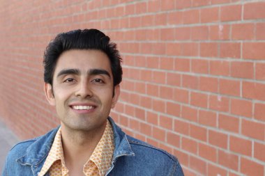 Kırmızı tuğla duvarın arka planında iyi bir adamın yakın plan portresi.