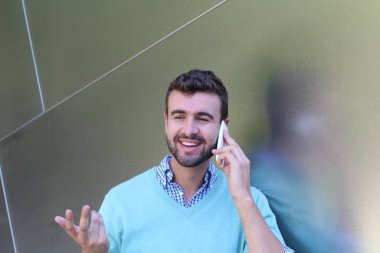 Kareli gömlekli genç bir adamın portresi ve telefonda konuşan Cyan süveteri. 