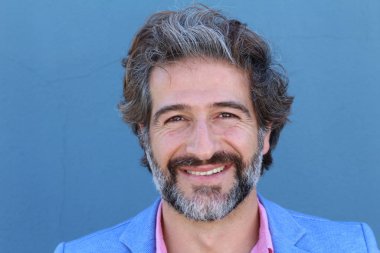 Mavi takım elbiseli ve mavi gömlekli yakışıklı bir iş adamının mavi duvarın önünde yakın plan portresi.