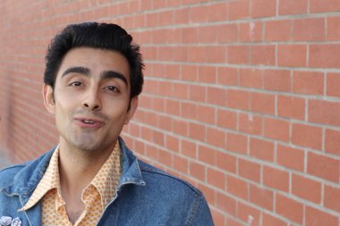 Kırmızı tuğla duvarın arka planında iyi bir adamın yakın plan portresi.