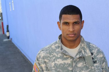 Mavi duvarın önünde üniformalı yakışıklı Afro-Amerikan askerinin yakın plan portresi
