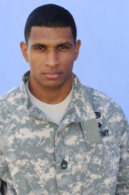 Mavi duvarın önünde üniformalı yakışıklı Afro-Amerikan askerinin yakın plan portresi