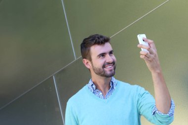 Kareli gömlekli genç bir adamın portresi ve telefonda konuşan Cyan süveteri. 