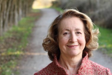 Olgun bir kadın gündüz vakti parkta duruyor.