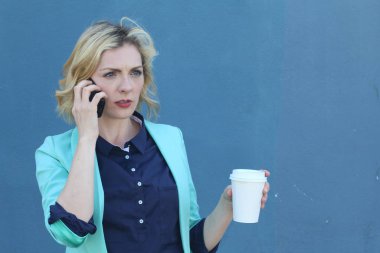 Başarılı bir iş kadını ofisinin önünde durmuş, telefonda konuşuyor ve iyi haberleri dinliyor. Çok mutlu.