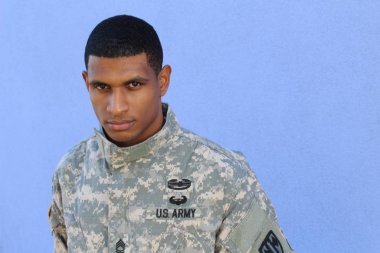 Mavi duvarın önünde üniformalı yakışıklı Afro-Amerikan askerinin yakın plan portresi
