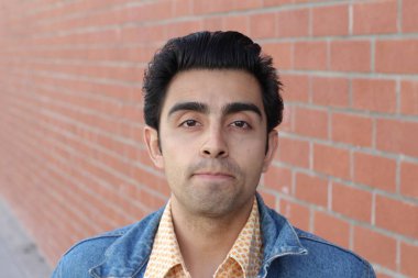 Kırmızı tuğla duvarın arka planında iyi bir adamın yakın plan portresi.