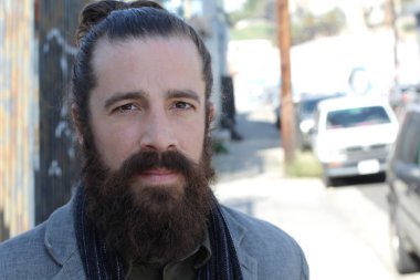 Tarz sahibi sakallı hippi modeli. Erkek saç stili, sokakta yaşam tarzı, tarlanın derinliği.