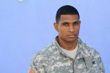 Mavi duvarın önünde üniformalı yakışıklı Afro-Amerikan askerinin yakın plan portresi