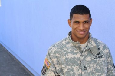 Mavi duvarın önünde üniformalı yakışıklı Afro-Amerikan askerinin yakın plan portresi