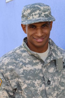 Mavi duvarın önünde üniformalı yakışıklı Afro-Amerikan askerinin yakın plan portresi