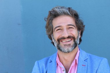 Mavi takım elbiseli ve mavi gömlekli yakışıklı bir iş adamının mavi duvarın önünde yakın plan portresi.