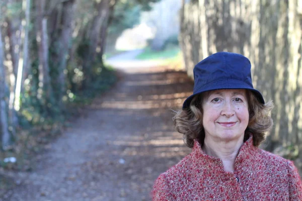 Olgun bir kadın gündüz vakti parkta duruyor.