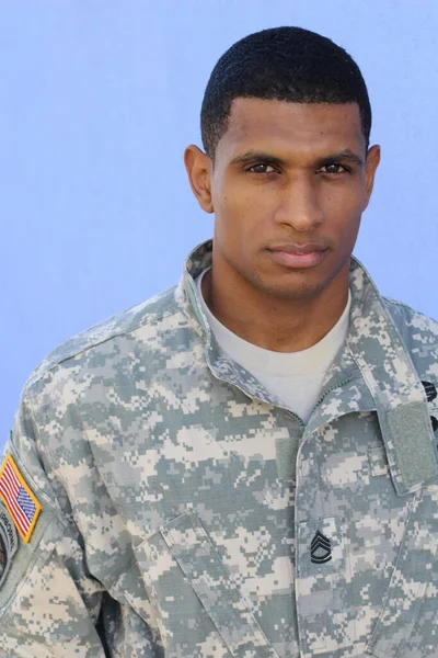 Mavi duvarın önünde üniformalı yakışıklı Afro-Amerikan askerinin yakın plan portresi