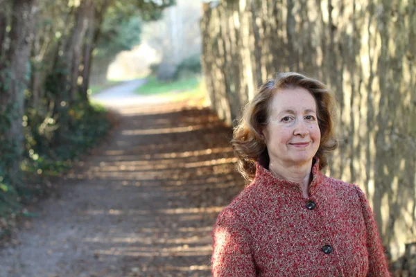 Olgun bir kadın gündüz vakti parkta duruyor.