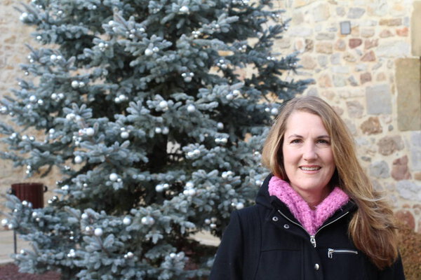 Улыбающаяся блондинка, стоящая в осеннем парке на фоне елки
 