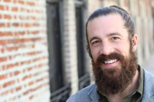 Stylish bearded hipster model with man bun hairstyle, lifestyle in the street, depth of field