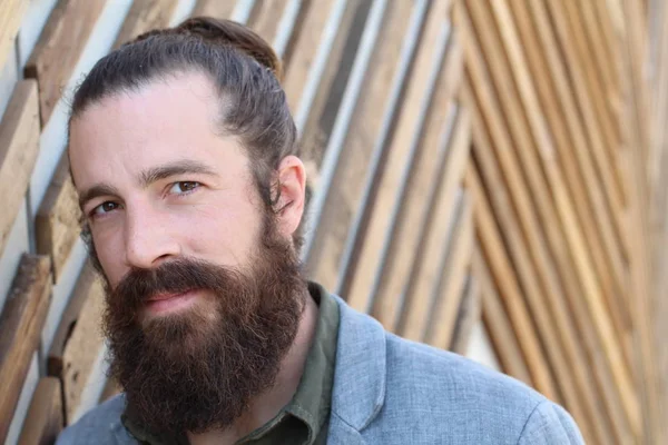 Stylish bearded hipster model with man bun hairstyle, lifestyle in the street, depth of field