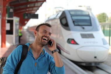 Tren istasyonunda trenini beklerken telefonda konuşan yakışıklı sakallı adam.