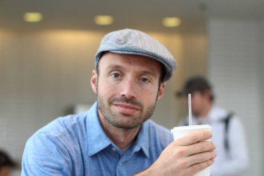 Closeup of handsome man with hipster look drinking coffee in cafe