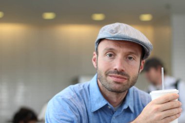 Closeup of handsome man with hipster look drinking coffee in cafe