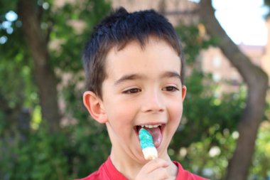 Gün ortasında parkta şeker yiyen şirin küçük çocuk. 