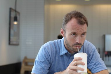 Closeup of handsome man drinking coffee in cafe