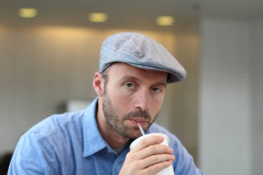 Closeup of handsome man with hipster look drinking coffee in cafe