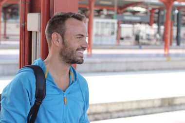 Tren istasyonunda bekleyen yakışıklı sakallı adam.