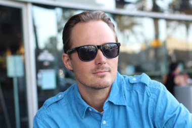 Kafede oturan güneş gözlüklü adam. 