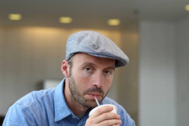 Closeup of handsome man with hipster look drinking coffee in cafe