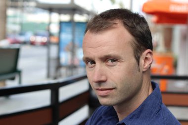 Şehirde yürüyen, arka planda bulanık genç bir adamın açık hava portresi. 