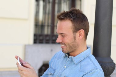 Yakışıklı, olgun bir adamın sokakta akıllı telefon kullandığı yakın plan portresi.