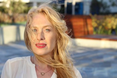 Akşam vakti şehirde caddede dikilen olgun sarışın kadın. 