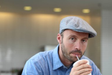 Closeup of handsome man with hipster look drinking coffee in cafe