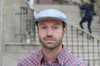 Dışarıda duran şapkalı yakışıklı sakallı adamın portresi.