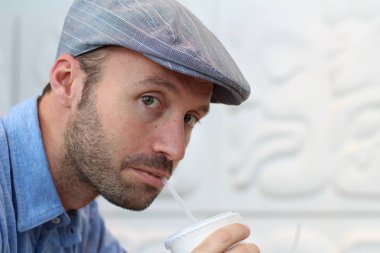 Closeup of handsome man with hipster look drinking coffee in cafe