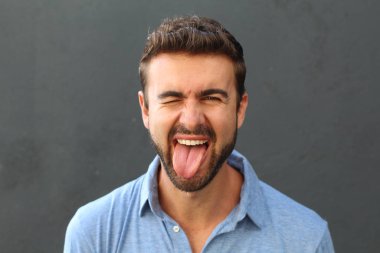 Gri arka planda duran mavi polo tişörtlü şirin bir adamın portresi. 