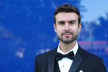 Takım elbiseli göz kamaştırıcı adam şehir geçmişinde duruyor. 