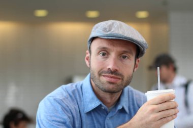 Closeup of handsome man with hipster look drinking coffee in cafe