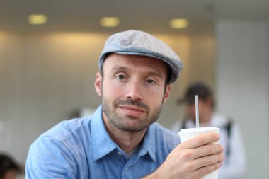 Closeup of handsome man with hipster look drinking coffee in cafe