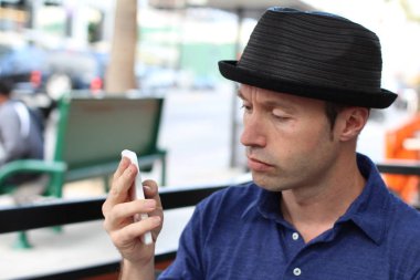 Şapkalı şık adam dışarıda selfie çekiyor.