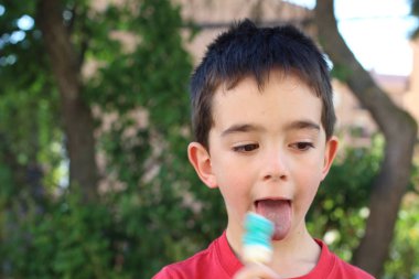 Gün ortasında parkta şeker yiyen şirin küçük çocuk. 