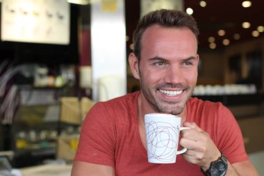 Kafede oturan ve gülümseyen yakışıklı bir gencin yakın plan portresi.