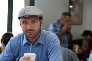 Closeup of handsome man with hipster look drinking coffee in cafe