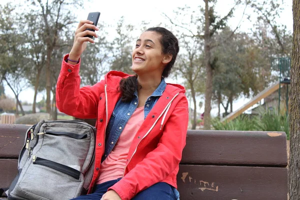 a woman with a backpack taking selfie with her phone