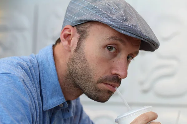Closeup of handsome man with hipster look drinking coffee in cafe