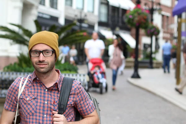 Outdoor portrait of hip man wearing eyeglasses and hat